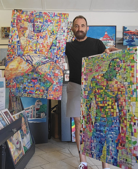 RD Riccoboni holding two Beartropolis Aerial Flyover Map giclées in his studio at Spanish Village Art Center, Balboa Park